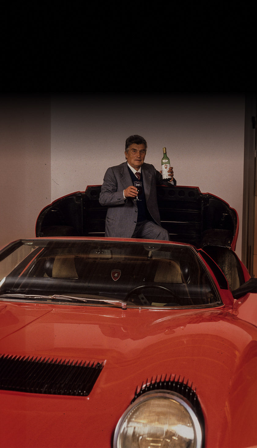 Ferruccio Lamborghini holding a bottle of wine and a glass