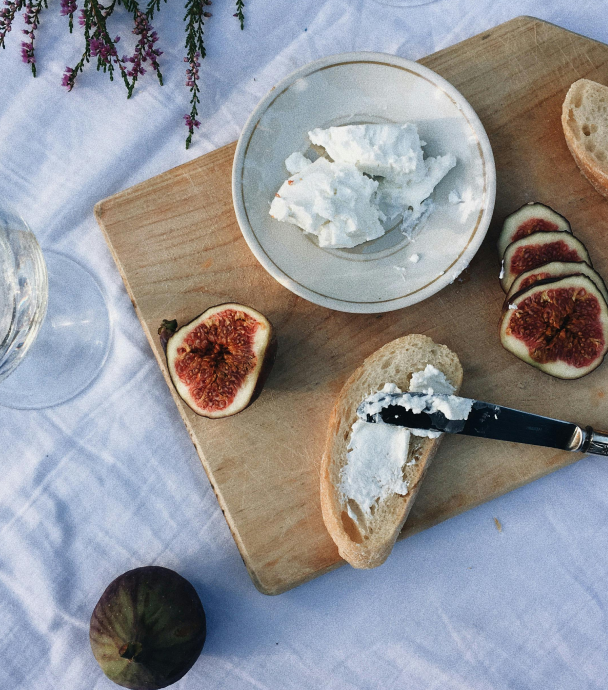 Board with cheese, figs, and slices of bread