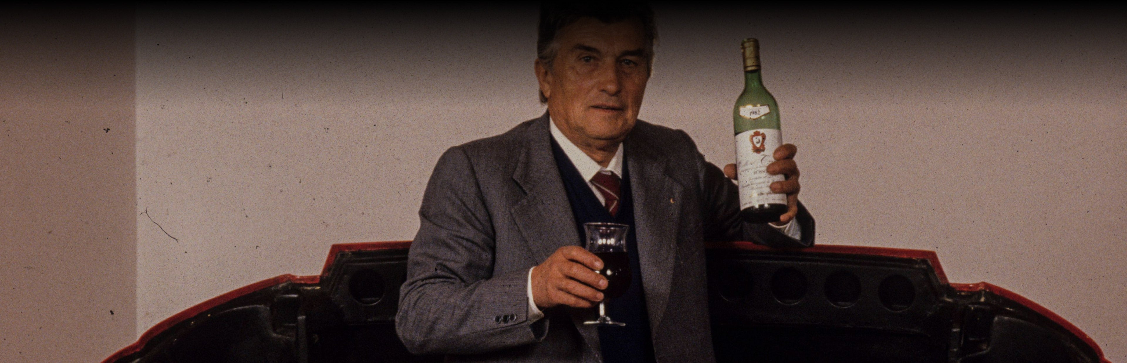 Ferruccio Lamborghini holding a bottle of wine and a glass